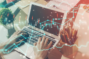 Double exposure of stock graph with businessman typing on computer in office on background. Concept of hard work.