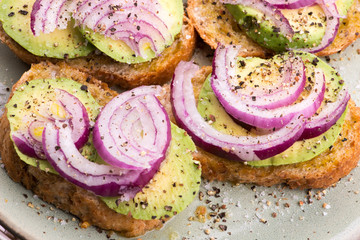 Sandwich with fresh avocado and onion on a plate