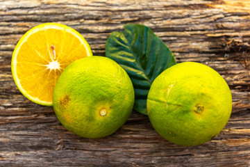 Fresh orange fruits around orange leaves on a wooden background