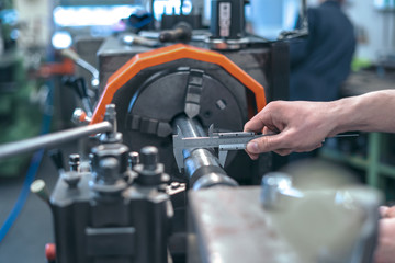 Industrie / Facharbeiter kontrolliert die Abmessung des Werkstoffes / Messen des Durchmesser mit dem Messschieber