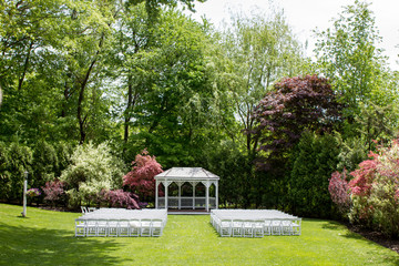 A pretty wedding ceremony location with a gazebo and flowering trees surround.