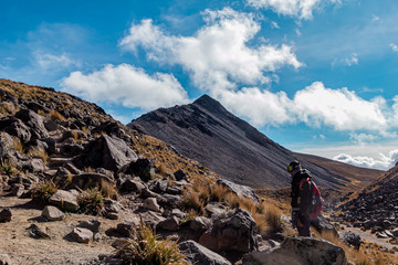 Montañista en paisaje montañoso volcánico con nubes en el fondo