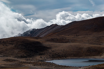 Paisaje volcánico de montañas, nubes y laguna