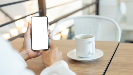 Mockup image blank white screen cell phone.woman hand holding texting using mobile on desk at coffee shop.background empty space for advertise text.people contact marketing business,technology