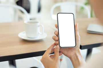 Mockup image blank white screen cell phone.woman hand holding texting using mobile on desk at coffee shop.background empty space for advertise text.people contact marketing business,technology