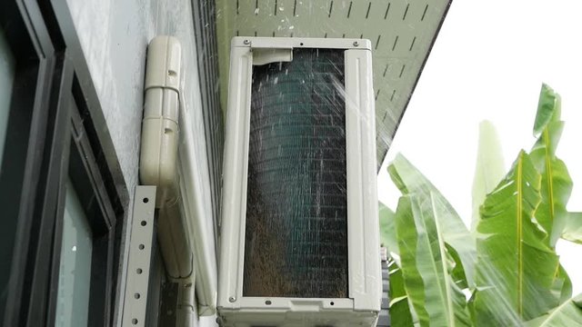 Cleaning air conditioning unit heat sink is dirty with squirt water. Scene is camera dolly in