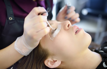 Obraz na płótnie Canvas Beautician making eyelash lamination procedures. Modern eyelash care treatment procedures - staining, curling, laminating and extension for lashes.
