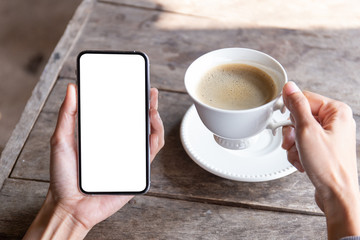 Fototapeta na wymiar Mockup image blank white screen cell phone.woman hand holding texting using mobile on desk at coffee shop.background empty space for advertise text.people contact marketing business,technology