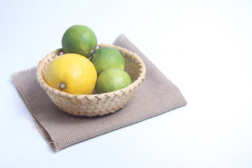 citrus fruits in a basket on canvas napkin isolated on white background flat lay