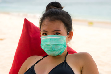 use of medical face mask in public places- young attractive Asian Korean woman enjoying beach...