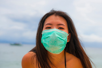 use of medical face mask in public places- young attractive Asian Korean woman enjoying beach...