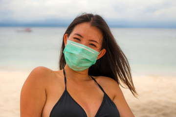 use of medical face mask in public places- young attractive Asian Korean woman enjoying beach...