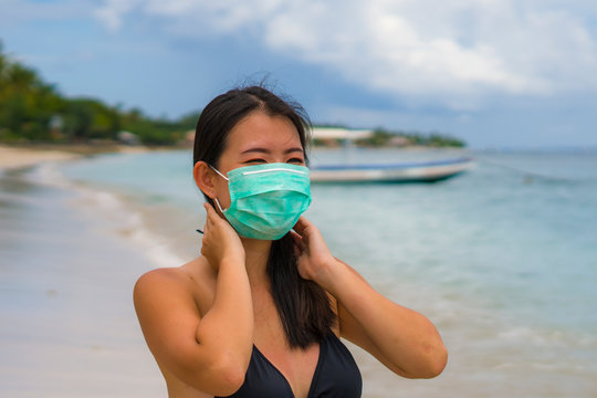 Use Of Medical Face Mask In Public Places- Young Attractive Asian Korean Woman Enjoying Beach Holidays In Bikini And Protective Facial Mask In Prevention Vs Virus Infection