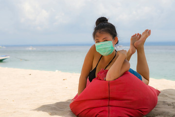 use of medical face mask in public places- young attractive Asian Chinese woman enjoying beach...