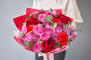 Bright berry color, Beautiful bouquet of mixed flowers in womans hands. the work of the florist at a flower shop. Delivery fresh cut flower. European floral shop.