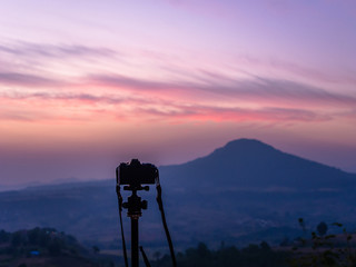 silhouette of tripod and camera is capturing the beautiful view of the mountain range in the morning.