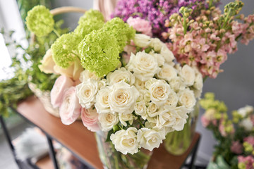Floral shop concept . Florist woman creates flower arrangement in a wicker basket. Beautiful bouquet of mixed flowers. Handsome fresh bunch. Flowers delivery.