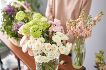 Floral shop concept . Florist woman creates flower arrangement in a wicker basket. Beautiful bouquet of mixed flowers. Handsome fresh bunch. Flowers delivery.