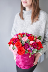 Red and violet floral bunch in Velour round box. European floral shop. Bouquet of beautiful Mixed flowers in woman hand.