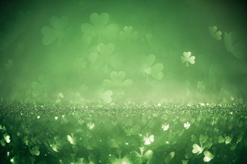 Green St Patricks day background with sparkling shamrock shapes - obrazy, fototapety, plakaty