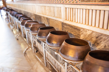 Obraz premium Closeup view of row of many bronze bowls standing on long stand in Buddhist temple