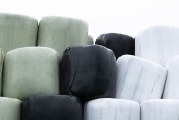 Stacked Piles of Large round hay bales wrapped in black, white and green  Plastic 