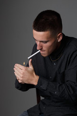 Single young Caucasian male teenager lighting a cigarette to start smoking