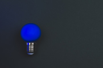 Blue light bulb on the dark background