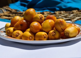 yellow unripe dates sweet fruit in plate close up, nature energy source diet healthy nutrition food