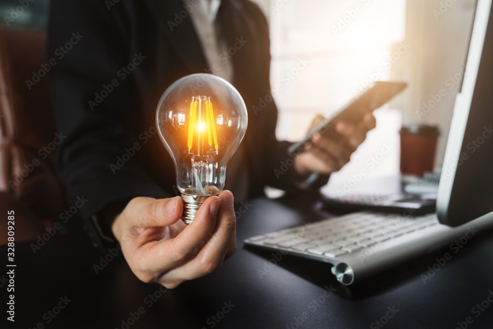 Poster business man hand holding lightbulb with using smartphone and calculator to calculate and money stac