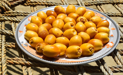 yellow unripe dates sweet fruit in plate close up, nature energy source diet healthy nutrition food