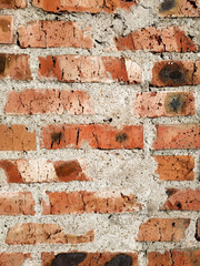 Background of red brick wall pattern texture near.An approximate photo of a vertical wall with bricks and cement. There are black spots on the Kerpichs, a granfoot for social networks, design projects