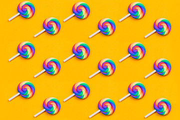 Lollipops are in a row. spiral candy pattern. lots of sweets on a yellow background. festive...