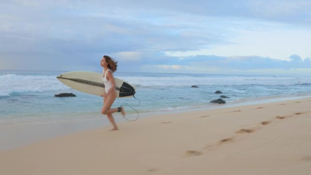 Surfer runs by Hawaiian beach, looking around for good waves, readiness for a surfing session
