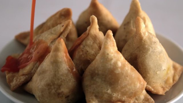 Indian samosas (Indian triangular pastry) ,  revolving against white background 