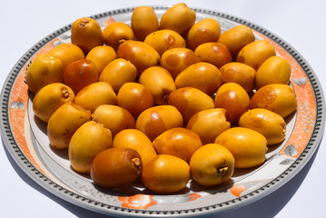 yellow unripe dates sweet fruit in plate close up, nature energy source diet healthy nutrition food