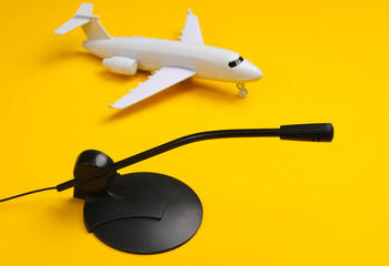 Air traffic controller, flight dispatcher. Plane figurine, microphone on a yellow background