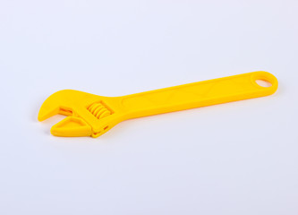 Yellow toy plastic wrench on white background close up
