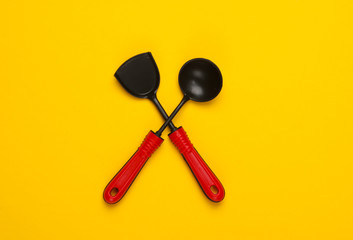 Toy kitchen tools on yellow background. Kitchen spatula, ladle. Top view