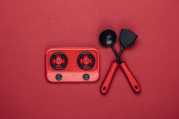 Toy stove and kitchen tools on a red background. Top view