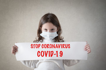 health care covid-19 epidemic outbreak concept of small girl in medical mask holding paper banner...