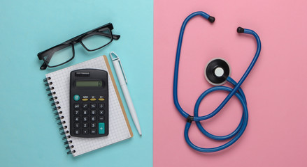 flat lay medical composition. Economic analysis. Calculator with notepad, stethoscope on a...