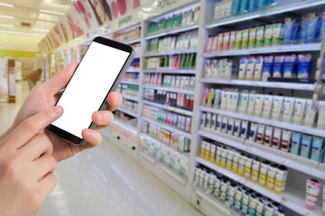 businessman holding blank screen for text on smartphone, mobile, cell phone with blurry cosmetics shelf background.