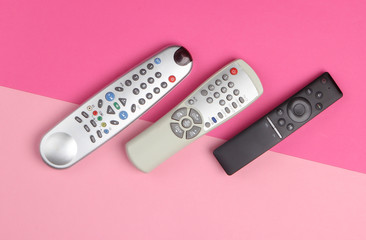 TV remotes on pink pastel background. Top view