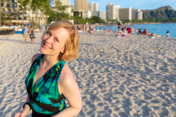 Portrait of a woman traveling in Hawaii and enjoying a day at the beach. She twirls on the sand and looks at the camera.