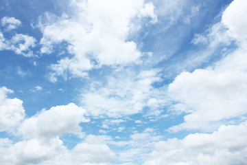 Many white clouds against bright blue sky on sunny day