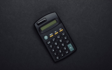 Black calculator on a black background. Top view