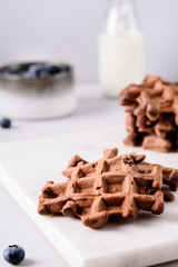 Homemade Chocolate waffles, milk and blueberries on white marble tray. Breakfast. Selective focus