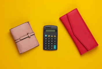 Calculator with leather wallets on yellow background. Family bujet, economical calculation, additional accounts of expenses. Top view