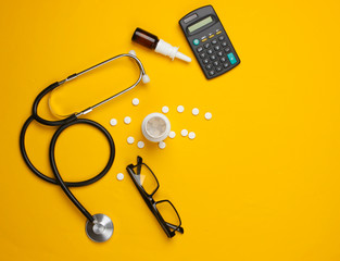 Doctoral supplies and tools, calculator on a yellow background. An economic calculation of the effectiveness of healthcare and medicine. Doctor workspace